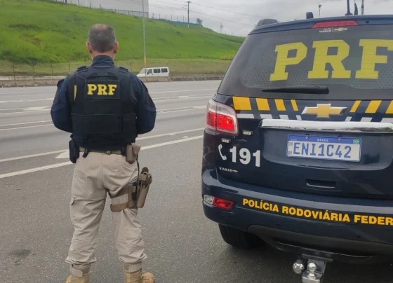 Oficial da PRF ao lado de viatura