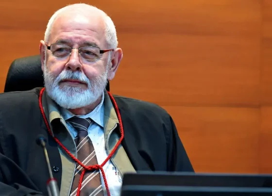 Foto horizontal que mostra o presidente do TJMT, desembargador José Zuquim Nogueira, sentado em seu posto no plenário do tribunal, olhando para o lado. Ele é um senhor branco, de cabelo e barba branca.