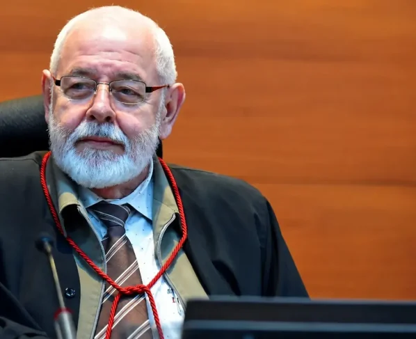 Foto horizontal que mostra o presidente do TJMT, desembargador José Zuquim Nogueira, sentado em seu posto no plenário do tribunal, olhando para o lado. Ele é um senhor branco, de cabelo e barba branca.