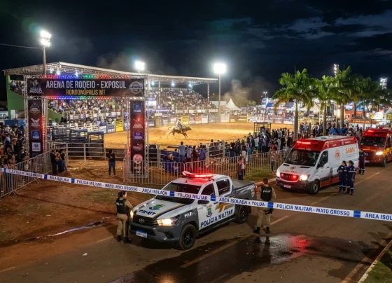 Arena de rodeio iluminada à noite com presença de viaturas de emergência e isolamento policial