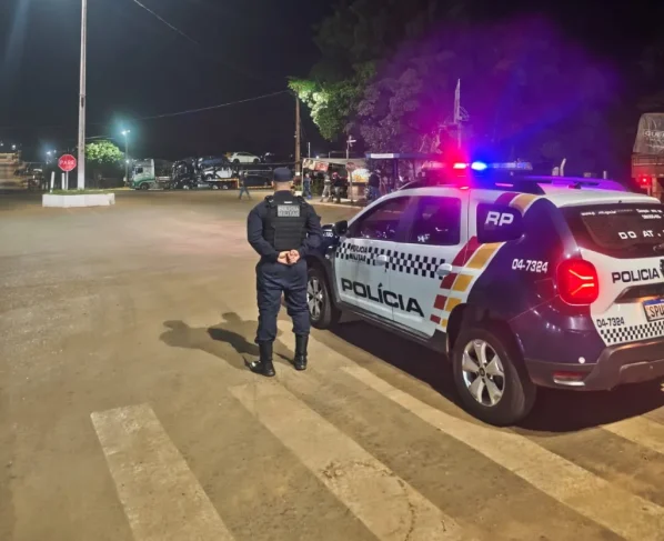 Policial militar ao lado de viatura